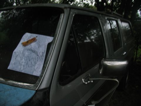 1978 Ford Bronco - A paper sign is taped to the windshield of a gray SUV.