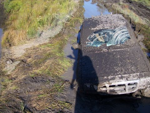 1996 Ford Bronco - This SUV is deeply stuck in mud, with its windshield covered in dirt.