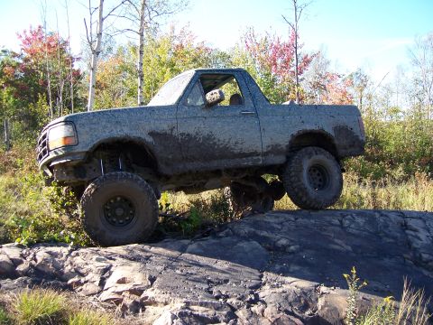 1996 Ford Bronco - This 1996 Ford Bronco is navigating a rocky trail with significant mud coverage.