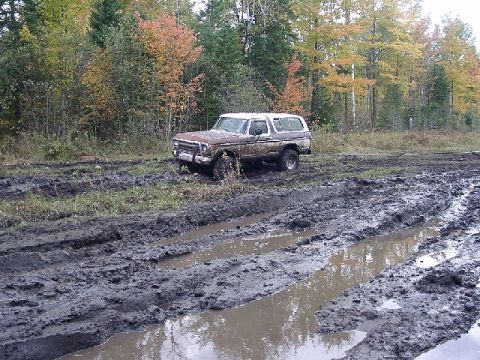 1978 Ford Bronco - A 1978 Ford Bronco navigates a muddy off-road trail during autumn.
