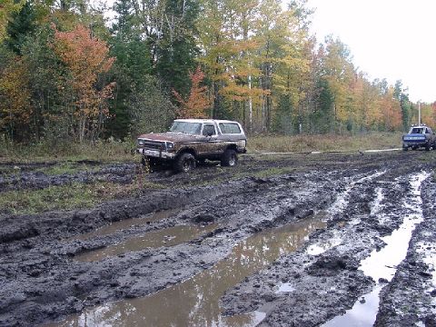 1978 Ford Bronco - A muddy scene shows a 1978 Ford Bronco navigating a difficult off-road path.