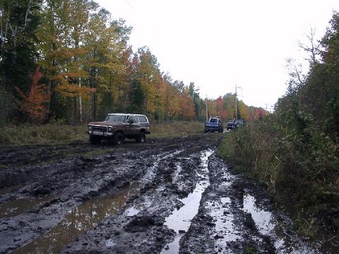 1978 Ford Bronco - Four-wheel drive vehicles navigate a challenging muddy path during autumn.