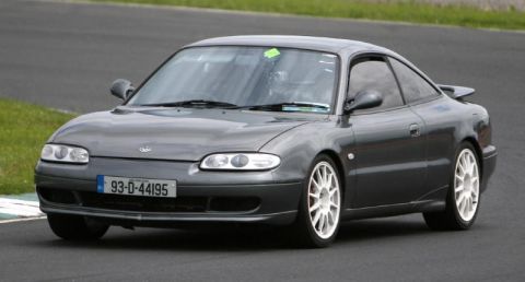 1991 Ford Probe - This dark gray coupe with white wheels is seen on a race track.