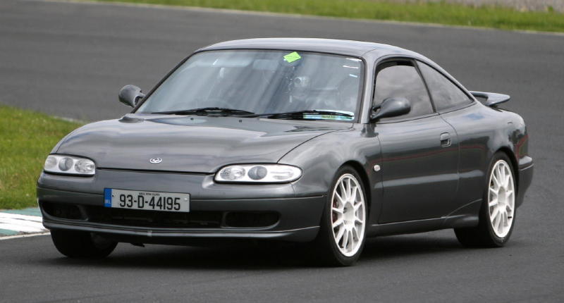 Dark gray coupe with white wheels on a race track