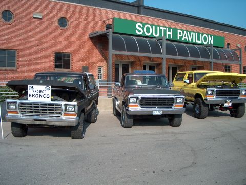 1978 Ford Bronco - Three Ford Bronco SUVs are parked outside the South Pavilion building on a sunny day.