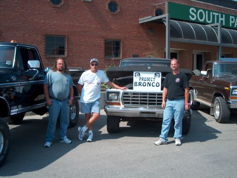 1978 Ford Bronco - Three men pose with a 1978 Ford Bronco, which has a sign on its grille reading "Project Bronco".
