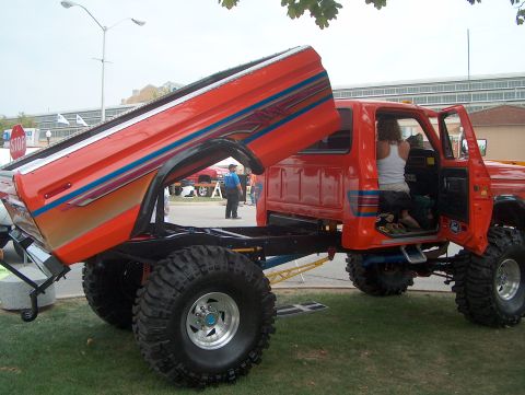 1978 Ford Bronco - Customized pickup truck with dump bed, large off-road tires and custom paint stripes.
