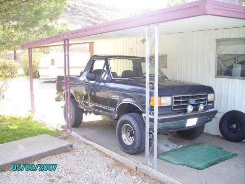 1990 Ford Bronco - This 1990 Ford Bronco is parked under a carport next to a trailer.