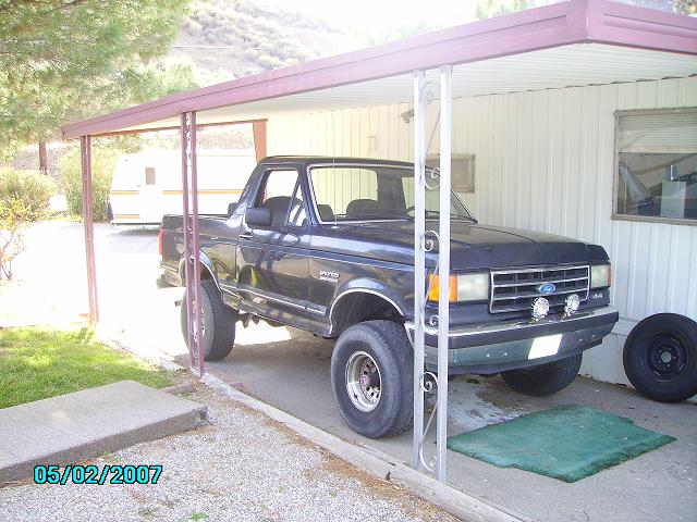 1990 Ford Bronco parked under a carport, front quarter view