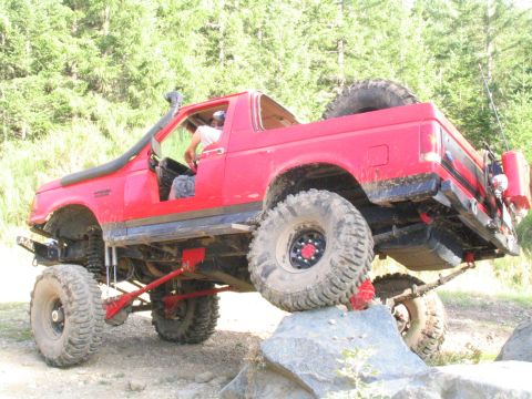 1989 Ford Bronco - This modified 1989 Ford Bronco navigates a rocky trail, equipped with a snorkel and a spare tire mounted on the rear.