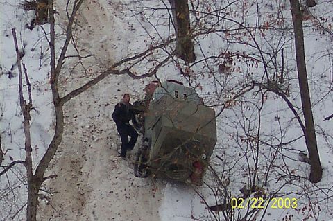 1978 Ford Bronco - A person stands by a vehicle that appears to be stuck in the snow on a wooded trail.