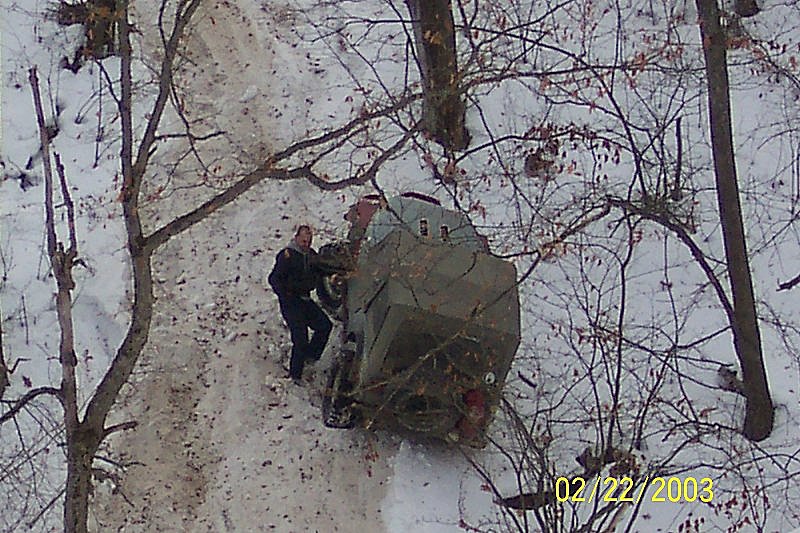 guy next to an off-road vehicle stuck on a snowy hill