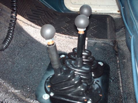 1982 Ford F-100 - Close-up of the floor console in a truck, showing multiple gear shifters and floor mats.