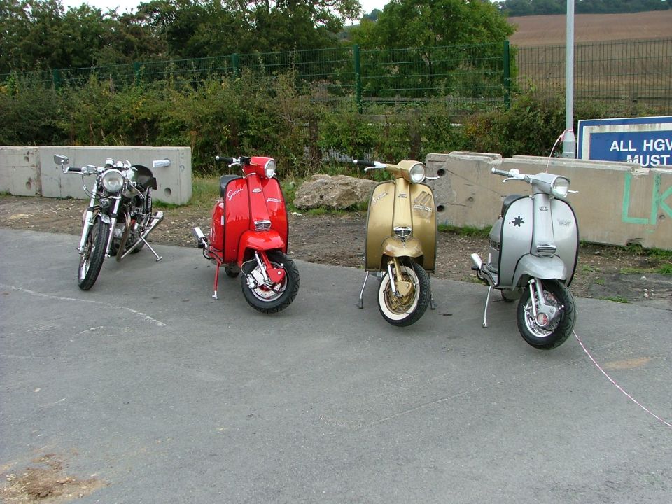 Motorcycle and three scooters parked on pavement