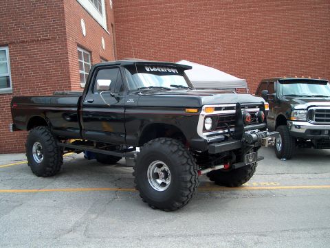 1978 Ford Bronco - This modified pickup truck features a lifted suspension and oversized off-road tires, parked outdoors.