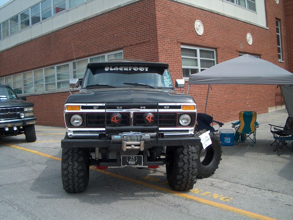 Black Ford truck with large tires and a winch, seen from the front