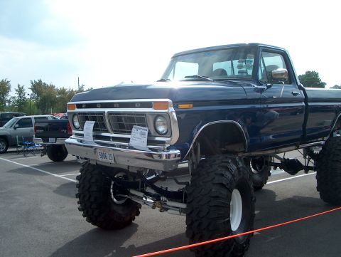 1978 Ford Bronco - A lifted blue Ford pickup truck is parked in a lot, with other vehicles visible in the background.