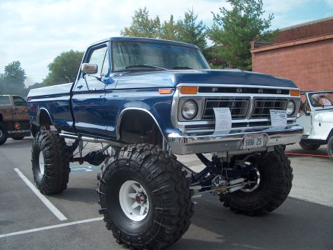1978 Ford Bronco - A lifted blue Ford pickup truck with oversized tires is displayed outdoors.