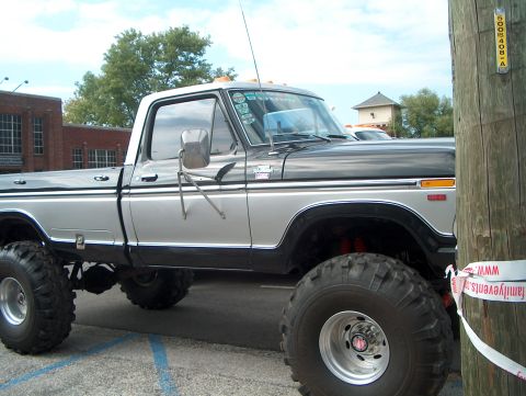 1978 Ford Bronco - A lifted pickup truck with a two-tone paint scheme is parked next to a wooden pole.