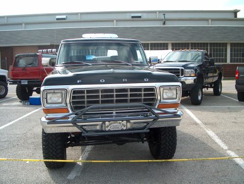 1978 Ford Bronco - Front view of a 1978 Ford Bronco, showing its grille and bumper. Multiple trucks are parked in the lot.