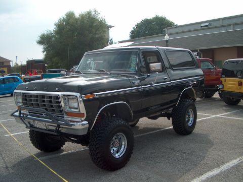 1978 Ford Bronco - A lifted black 1978 Ford Bronco is parked in a lot with other vehicles.