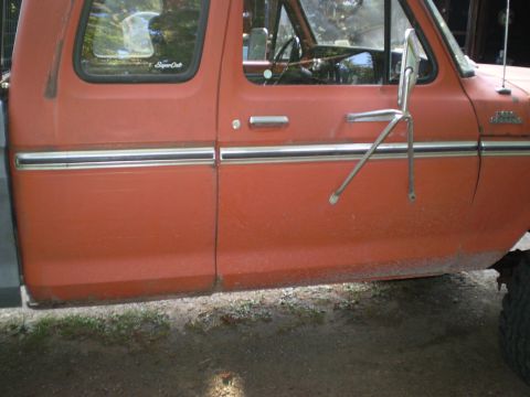 1979 Ford Bronco - Side view of an orange 1979 Ford F-Series truck door and fender with chrome trim.