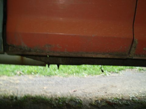 1979 Ford Bronco - The lower body panel of a vehicle shows extensive rust and damage, indicating poor condition.