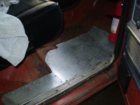 1979 Ford Bronco - Interior view of a vehicle's floor with a metal plate and a fire extinguisher visible.