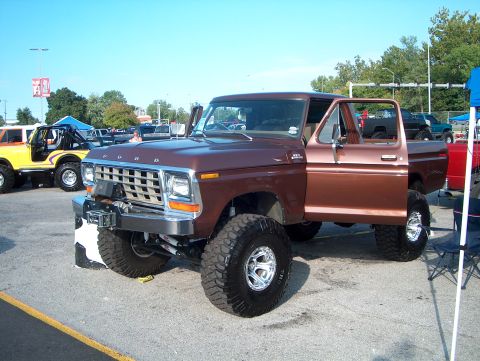 1978 Ford Bronco - Lifted 1978 Ford pickup truck with custom wheels and off-road tires. Another vehicle is parked nearby.
