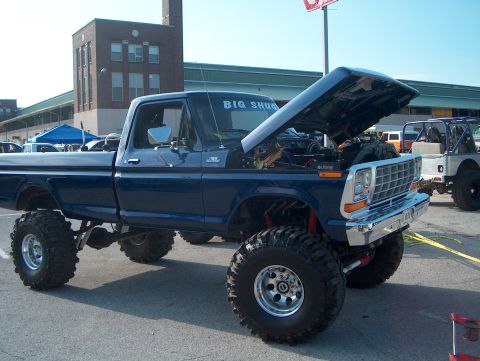 1978 Ford Bronco - A lifted blue pickup truck with its hood open is parked next to another off-road vehicle.