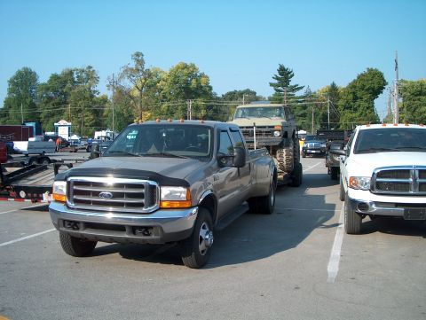 1978 Ford Bronco - A Ford F-350 tows a heavily modified Jeep, with a Dodge Ram parked nearby.