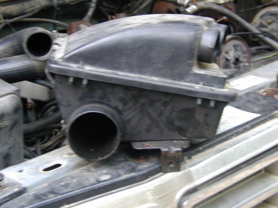 Black plastic air cleaner housing with two intake tubes, mounted on a vehicle's engine