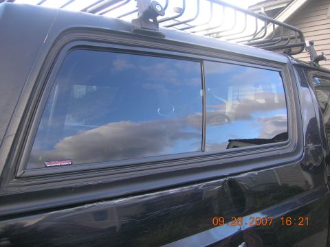 1996 Ford Bronco - Side view of a black SUV, showing a dented rear quarter panel and a roof rack.