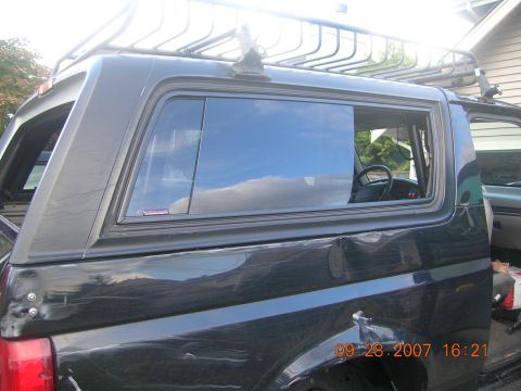 1996 Ford Bronco - This black SUV features a camper shell and a roof rack, with a date stamp visible on the body.