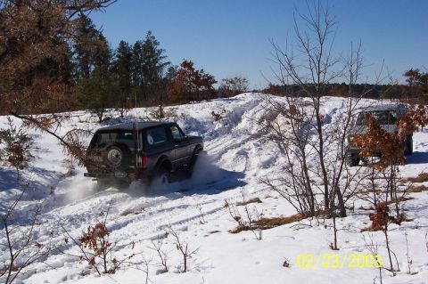 1978 Ford Bronco - Two SUVs navigate a snow-covered trail on a bright, clear day.