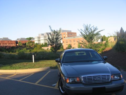 2000 Ford Crown Victoria - Front view of a dark gray 2000 Ford Crown Victoria parked in a lot with a modern building in the background.