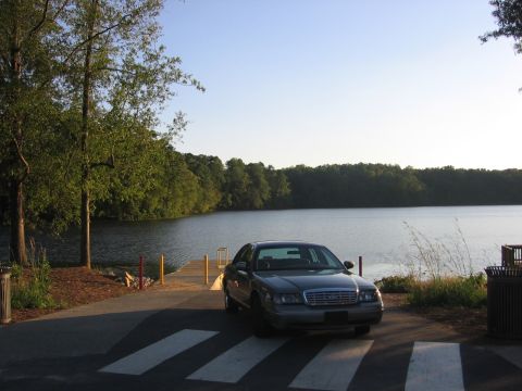 2000 Ford Crown Victoria - A gray 2000 Ford Crown Victoria is parked on a boat ramp with a lake in the background.