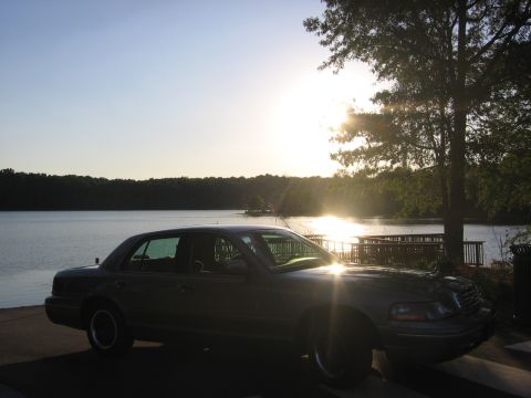 2000 Ford Crown Victoria - A dark 2000 Ford Crown Victoria is parked near a lake during a sunset.