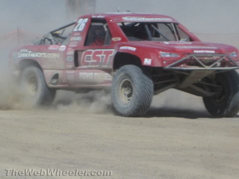 1990 Ford Bronco - red off-road race truck numbered 26 with CST and Toyo Tires graphics corners on a desert course.