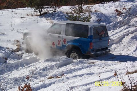 1978 Ford Bronco - A Ford Bronco II navigates a snowy terrain, its tires churning through the snow.