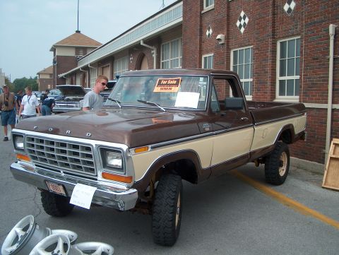 1978 Ford Bronco - A two-tone Ford pickup truck is parked outside a brick building, with a man standing nearby.