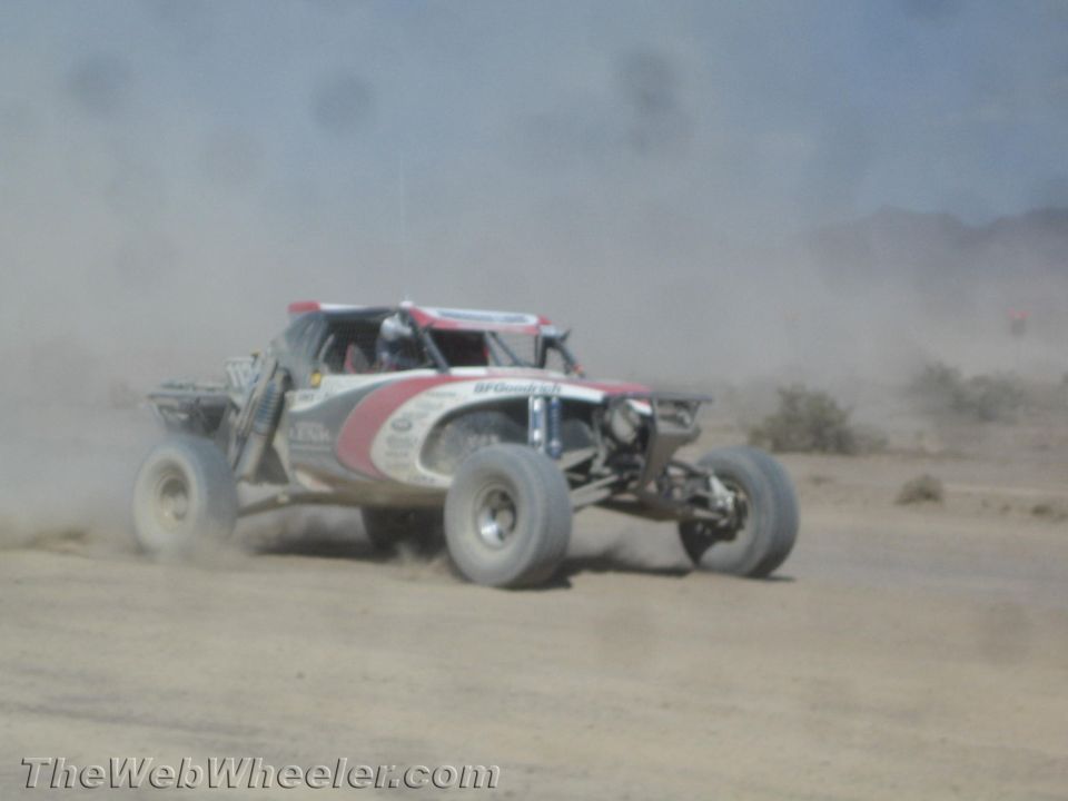 Red and white off-road race buggy speeding through dust
