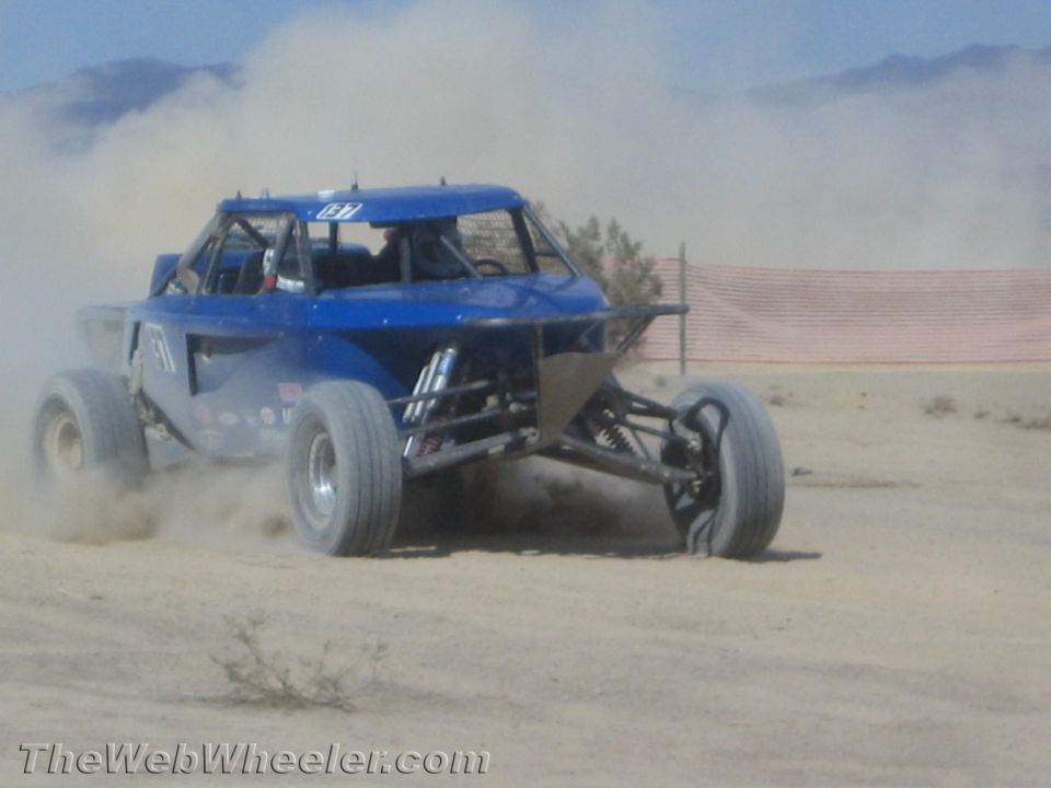 Blue off-road race buggy speeding across a desert flat