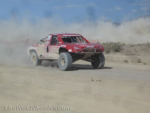 1990 Ford Bronco - red off-road race truck numbered 28 with ESP and Toyo Tires livery races along a dusty desert course.