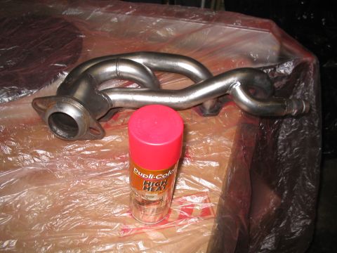 1989 Ford Bronco - An exhaust manifold and a can of high-heat paint are on a plastic-covered surface.