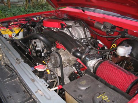 1989 Ford Bronco - Close-up of a V8 engine with a red aftermarket air filter and battery visible.