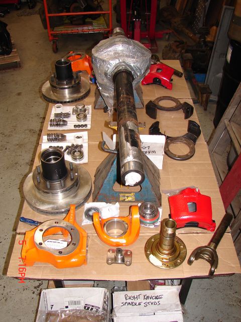 1989 Ford Bronco - Various vehicle axle and brake parts are laid out on cardboard for display or assembly.