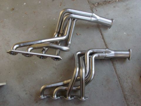 1979 Ford Bronco - A pair of exhaust headers are shown on a concrete surface, likely for an automotive engine.