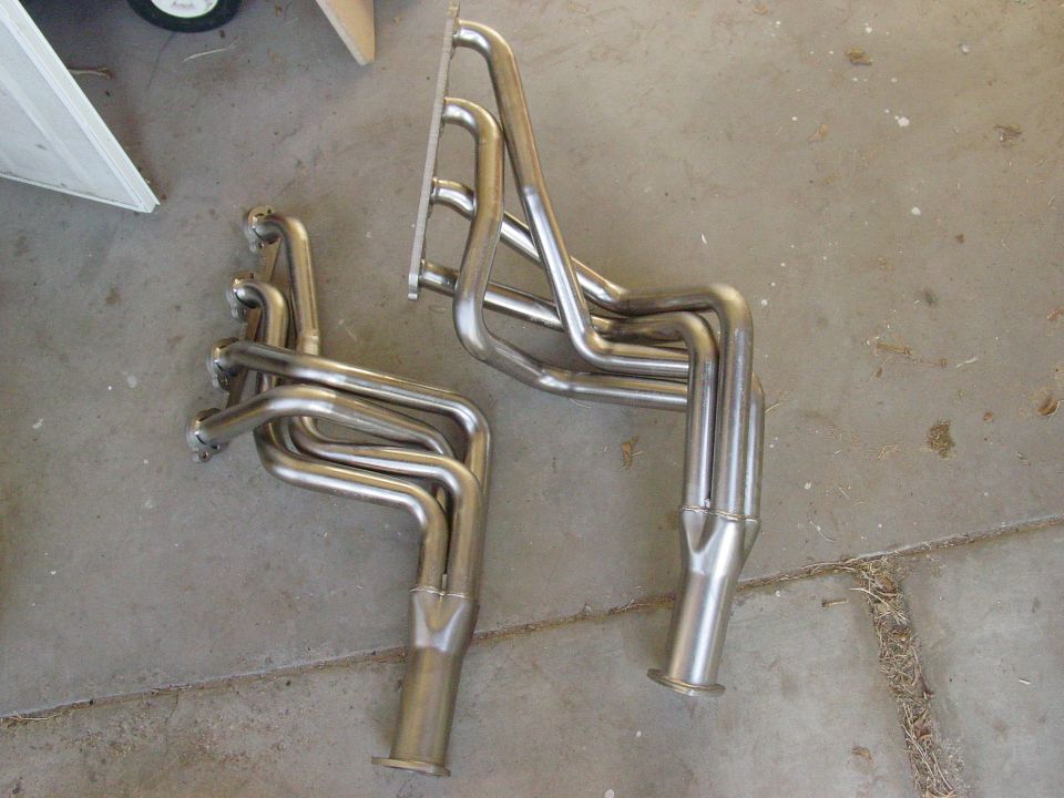 Two stainless steel exhaust headers on a concrete floor