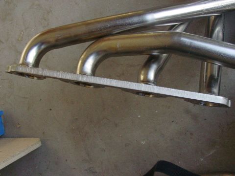 1979 Ford Bronco - Close-up view of a chrome exhaust manifold, likely an aftermarket part, with a flat mounting flange.